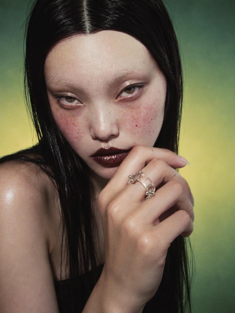 Double Pierced Glass Ring 0021, campaign photograph in green and yellow light, glass with two steel piercings, Rain and Rivers