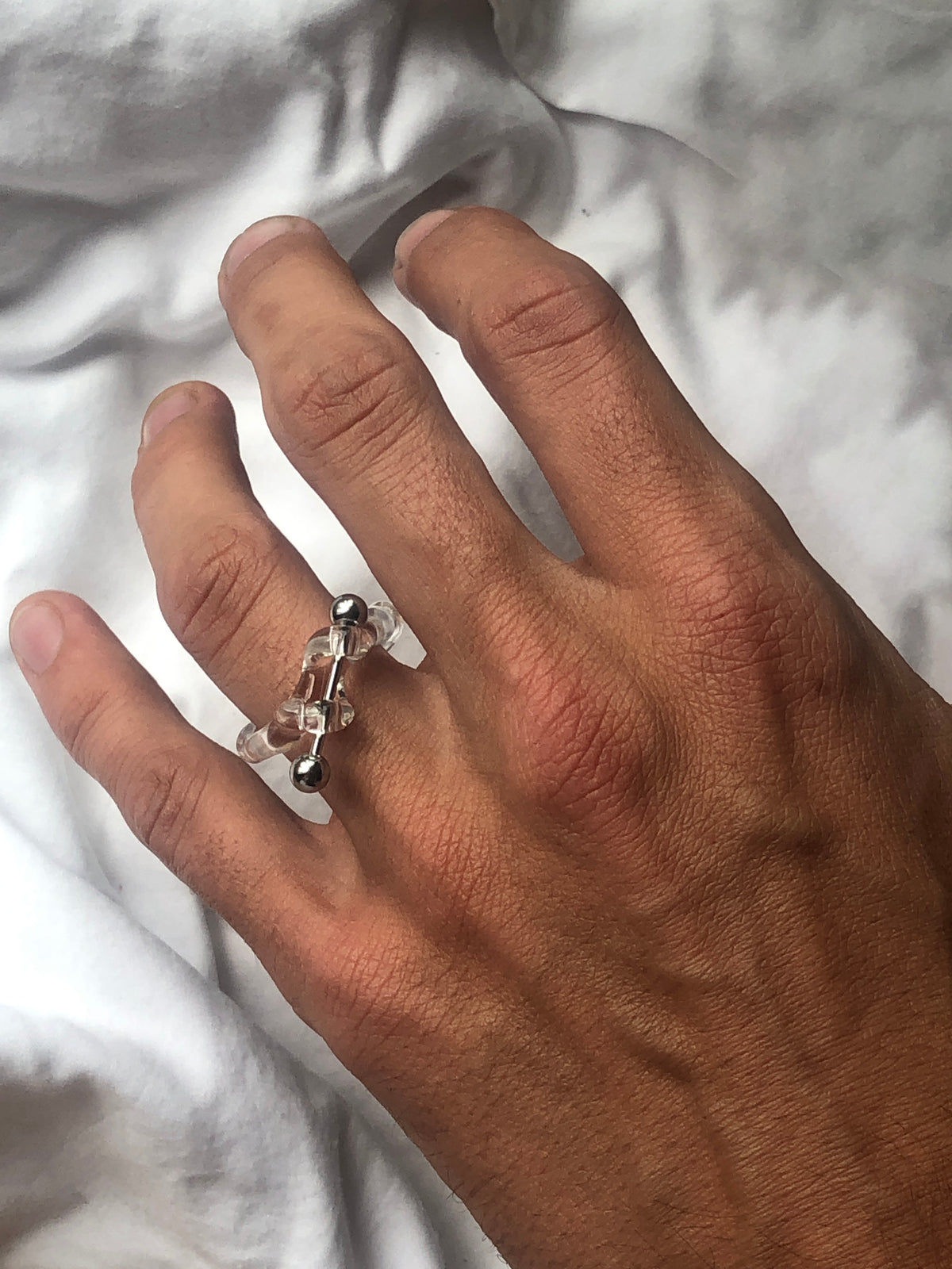 Barbell Piercing Glass Ring 0076 in clear hand-sculpted borosilicate glass with a stainless steel barbell, worn on the hand, Rain and Rivers