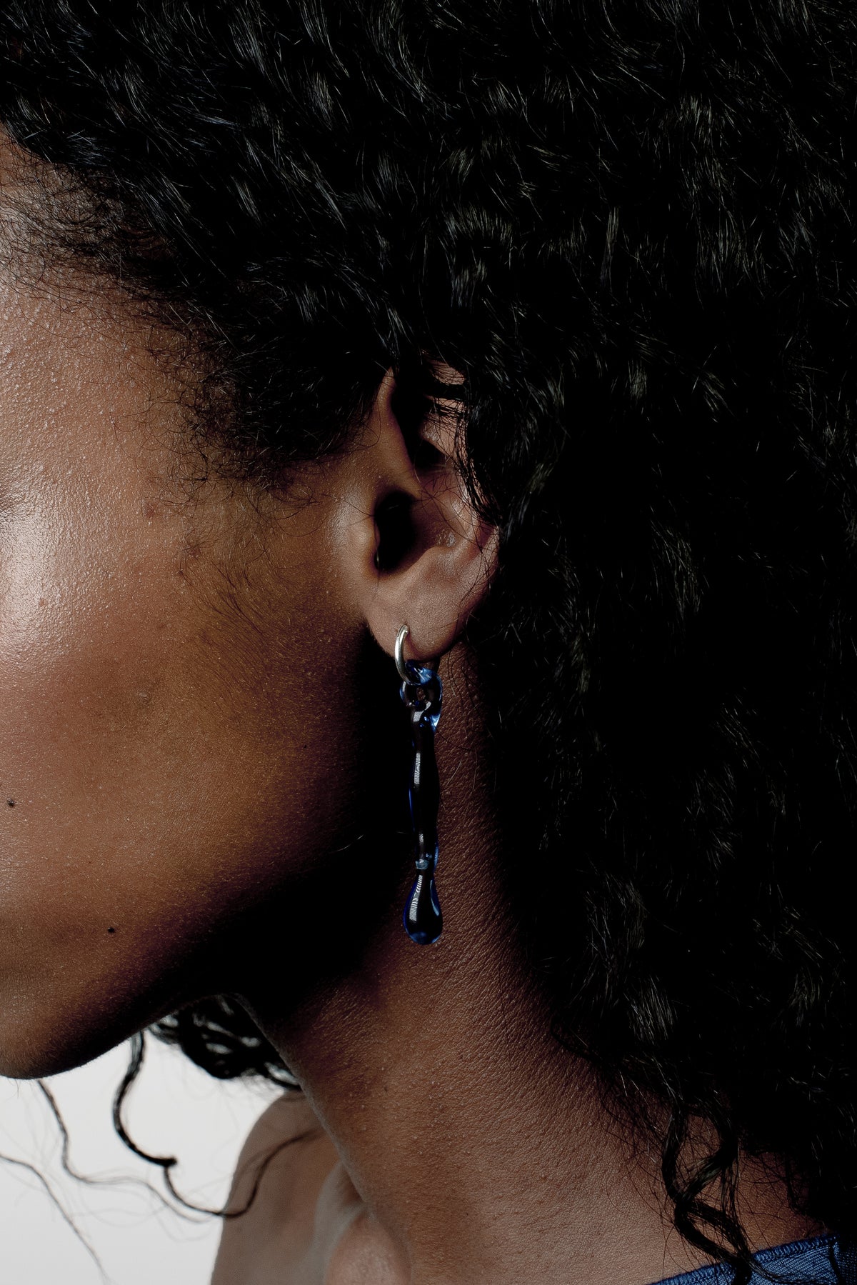 Hoop Earrings 0010 in sky blue glass worn on the ear, hand-sculpted borosilicate glass and sterling silver by Rain and Rivers, Barcelona