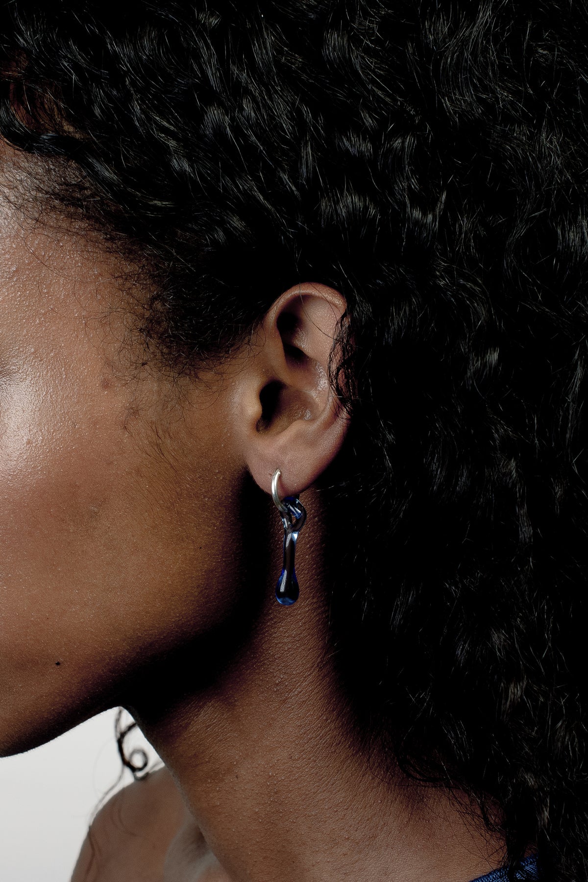 Mini Hoop Earrings 0012 in sky blue glass worn on the ear, hand-sculpted borosilicate glass and sterling silver by Rain and Rivers, Barcelona