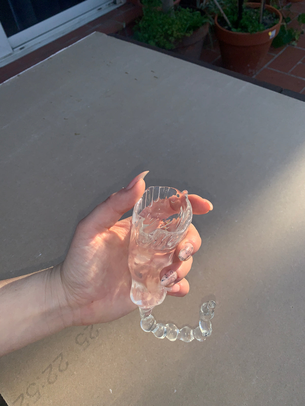 Glasses 0007 in clear hand-sculpted borosilicate glass, held in the hand, side view, Rain and Rivers