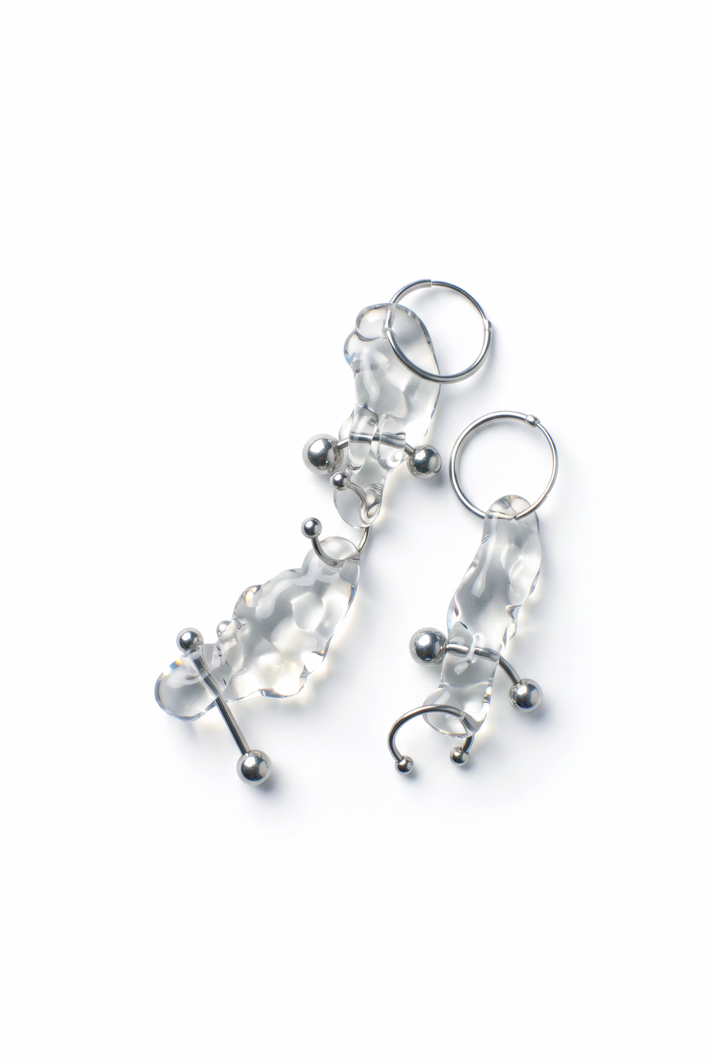 Rain and Rivers Glass Earrings 0023 – pair of hand-sculpted clear borosilicate glass earrings on steel hoops with stainless steel barbell and horseshoe piercings, handmade in Barcelona, product photo on white
