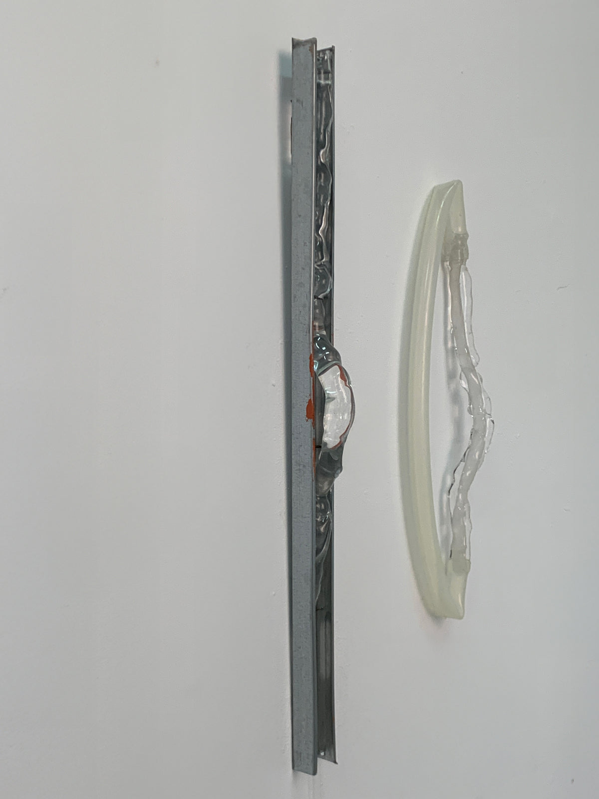 Blown glass wall sculpture hanging beside a steel rail